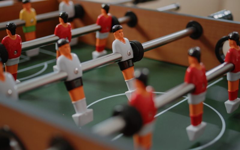 Close up of players on foosball game table for fun activity in office after work. Table with football game play to score goal for entertainment with workmates after hours. Soccer amusement